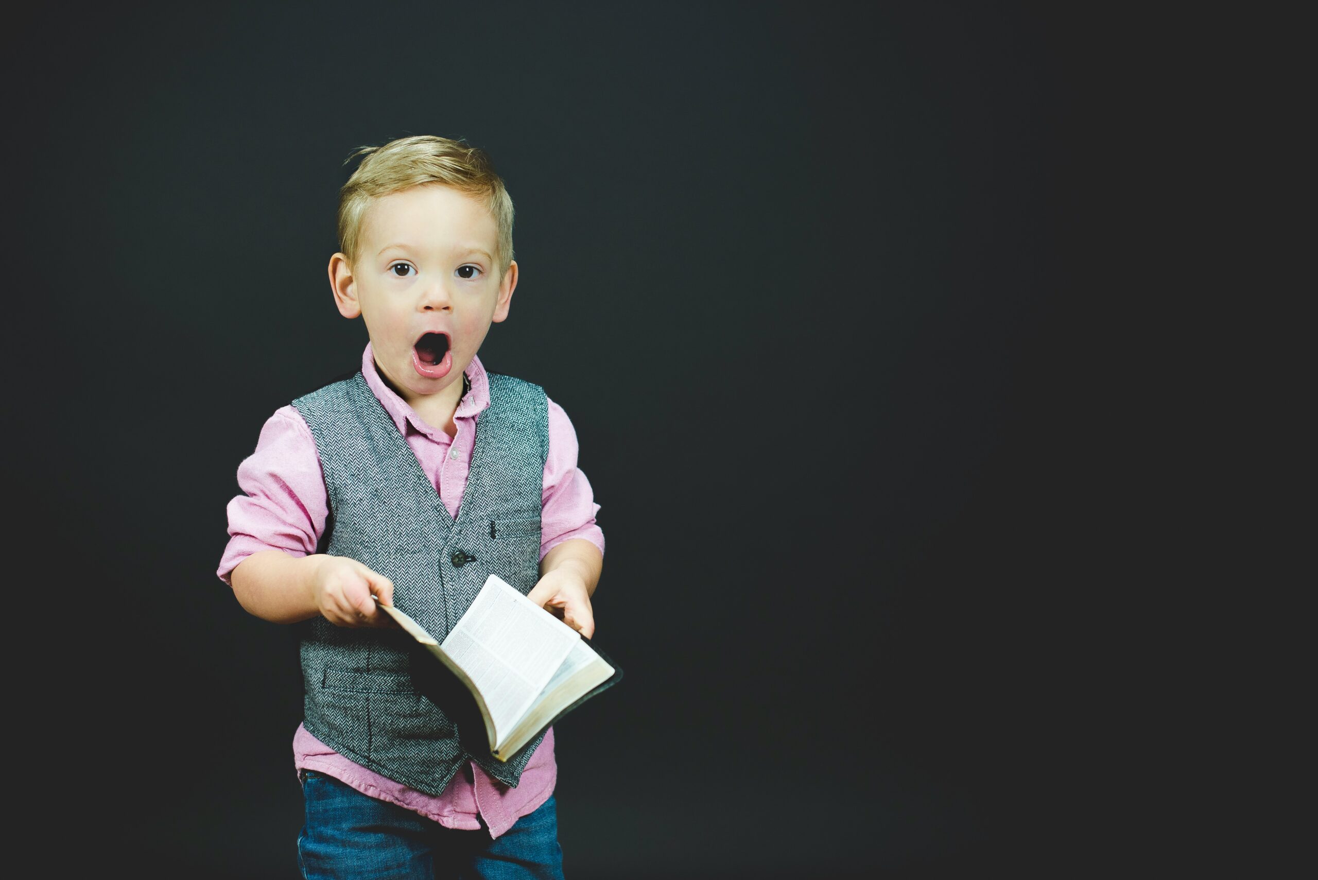 photo of a young boy all dressed up and surprised by something in a book