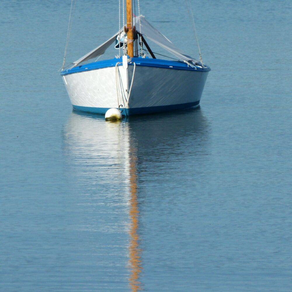 a lone sail boat anchored in the water