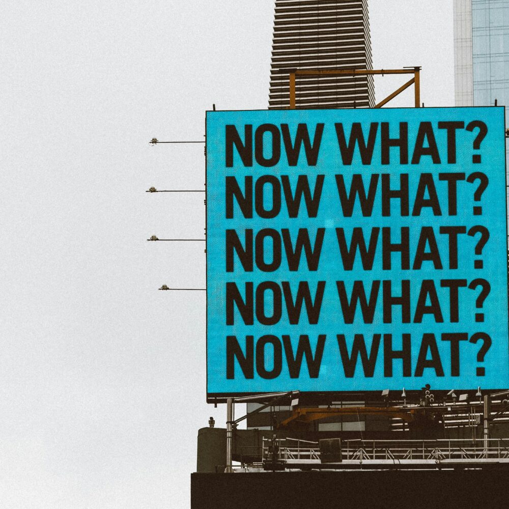 image of a square billboard repeating the message Now What?