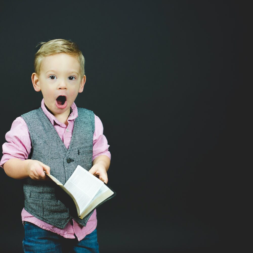 image of a young boy opening a book with a look of total surprise on his face